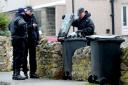 Police search bins outside homes close to the post office in Melsonby after the murder of Diana Garbutt