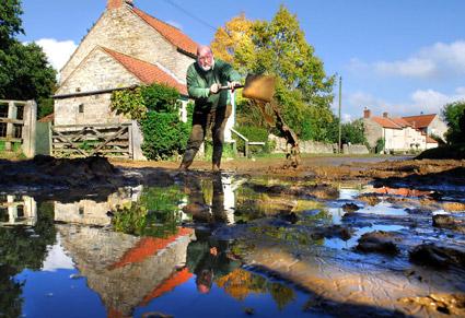 Ken Metcalfe, of Nunnington, tries to remove some of the mud from the street following the weekend's torrential rain. 