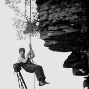 Cherry Kearton hanging off a cliff with his camera attached to his back, it shows the lengths the brothers went to get the perfect shot