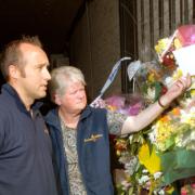 Paul Lodge and fellow Racing Welfare officer Janet Allison inspect the floral tributes at the gate to the flat in Norton where  young jockeys Jan Wilson and Jamie Kyne died in a fire