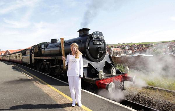  Kelly Williams standing in front of the steam locomotive The Green Knight, holding the Olympic Flame before its journey on the North Yorkshire Moors Railway, from Whitby to Pickering
