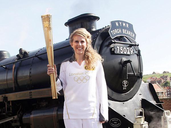  Kelly Williams standing in front of the steam locomotive The Green Knight, holding the Olympic Flame before its journey on the North Yorkshire Moors Railway, from Whitby to Pickering