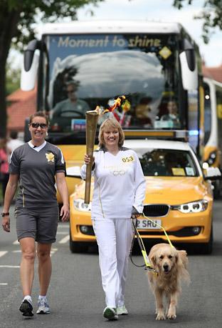 Alison Bates with her guide dog carries the Olympic Flame 