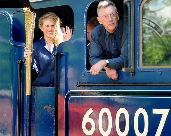 Kelly Williams carries the Olympic torch into Pickering's North Yorkshire Moors Railway station on board the Sir Nigel Gresley