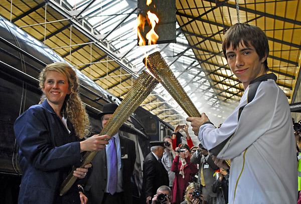 Kelly Williams who carried the Olympic torch into Pickering's North Yorkshire Moors Railway station on board the Sir Nigel Gresley hands over to Max Strachen of Durham