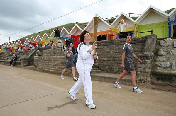 Jacqueline MacKenzie carries the Olympic Flame on the seafront at the North Bay in Scarborough