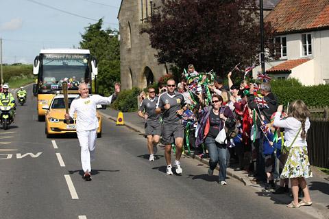 David Heppell carries the Olympic Flame on the Torch Relay leg between Hinderwell and Pickering
