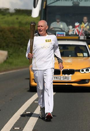 David Heppell carries the Olympic Flame on the Torch Relay leg between Hinderwell and Pickering
