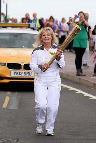 Sally Hutchinson carries the Olympic Flame on the Torch Relay leg between Scarborough and Filey