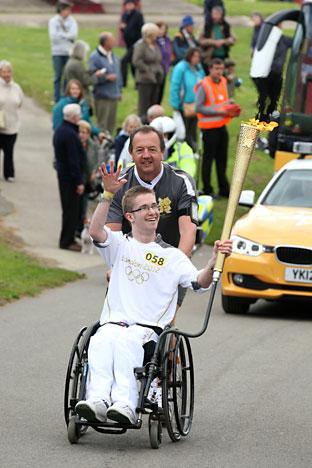 Jamie Green and chaperone carries the Olympic Flame on the Torch Relay leg through Scarborough. 