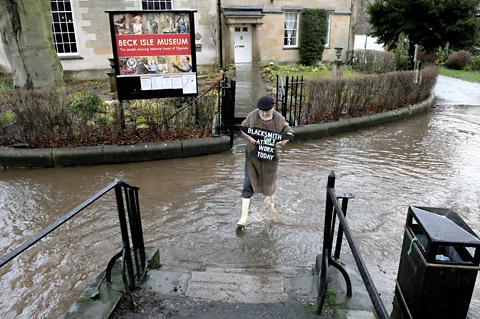 Blacksmith John Steele moves his sign to the front of the Beck Isle Museum which was surrounded by floodwater. 
