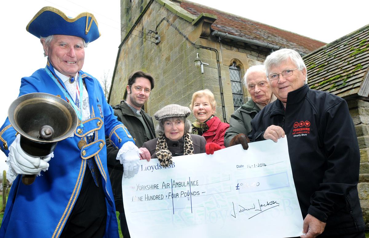 Malton and Norton town crier and churchwarden David Jackson hands over a cheque to Yorkshire Air Ambulance and St Andrew’s Church, in Normanby, of money raised from an auction of promises.