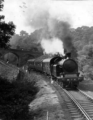 A steam locomotive pulls three carriages on the North Yorkshire Moors railway in the 1970s. 