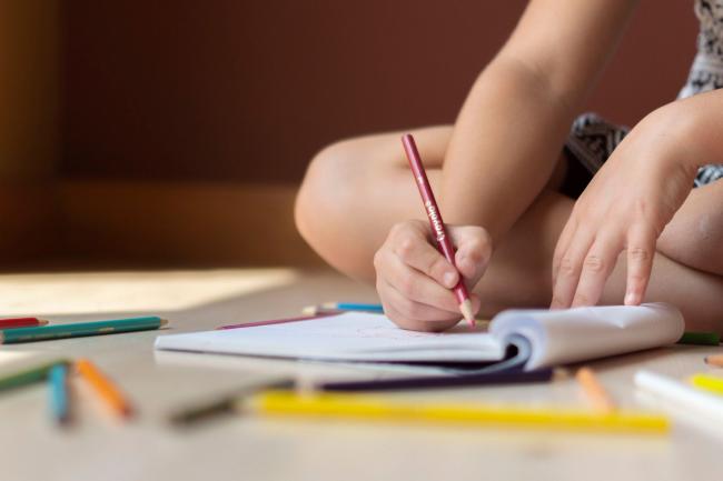 Photo via Canva shows a child alone drawing.