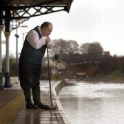 A station supervisor waits for levels to drop on the flooded rail tracks at Malton station