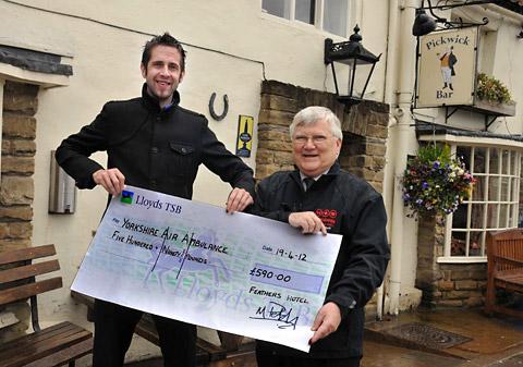 Bar staff member Matt Petch presents a cheque for £590 to Bob Smailes of the Yorkshire Air Ambulance. The
money was raised by staff and customers at The Pickwick Bar in the Feathers Hotel, Helmsley.