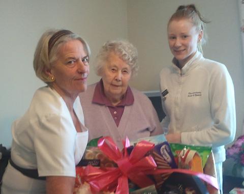 Level three beauty students at Deansfield Court in Norton,  Judith Porter, right, and Natalie
Donovan, present resident Mrs Lee with her winning food hamper.