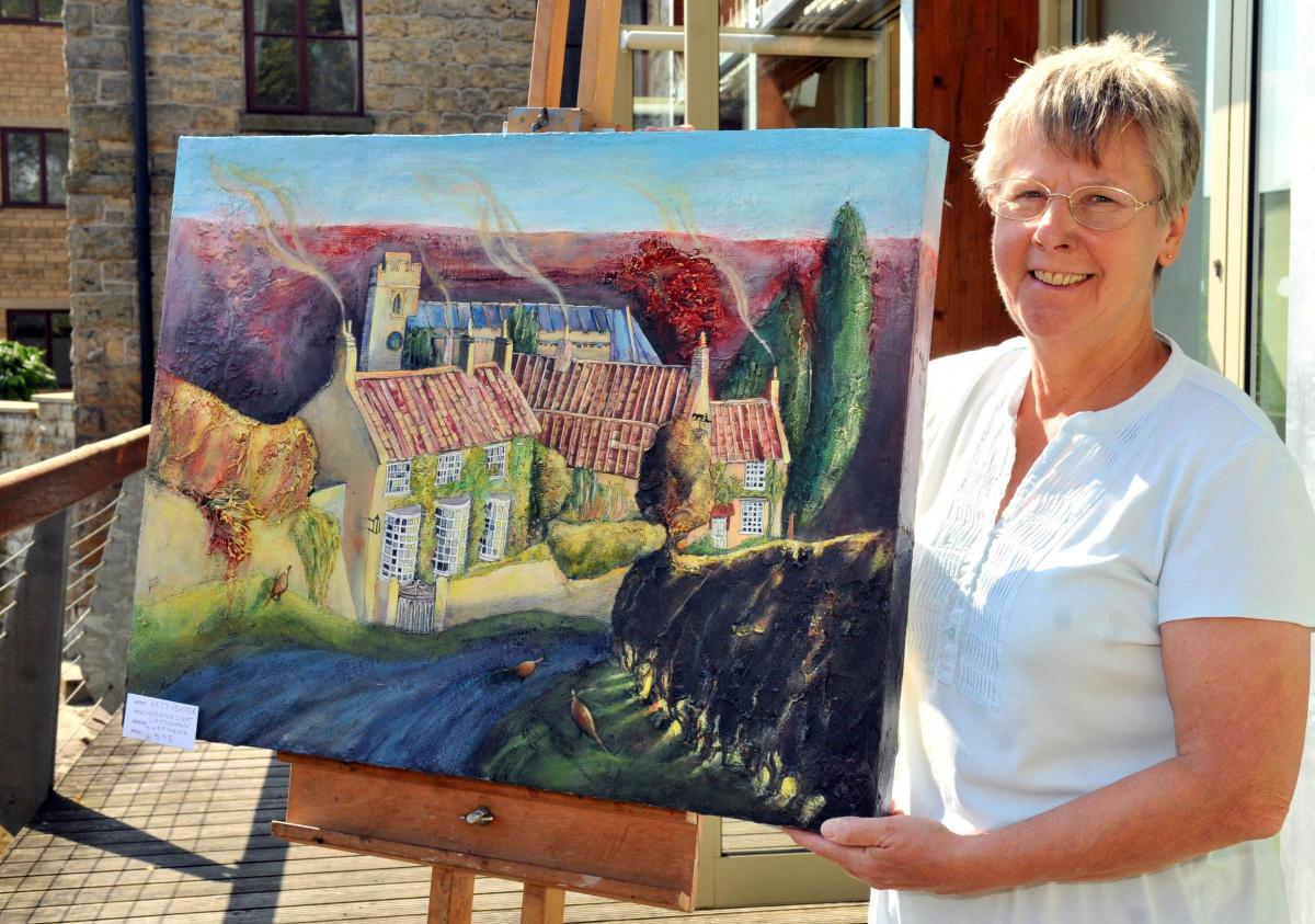Diana Smith, chairman and publicity officer of the Vale of Pickering Art Club, with a painting by Andrea Bailey, prepares for the club's annual exhibition.
